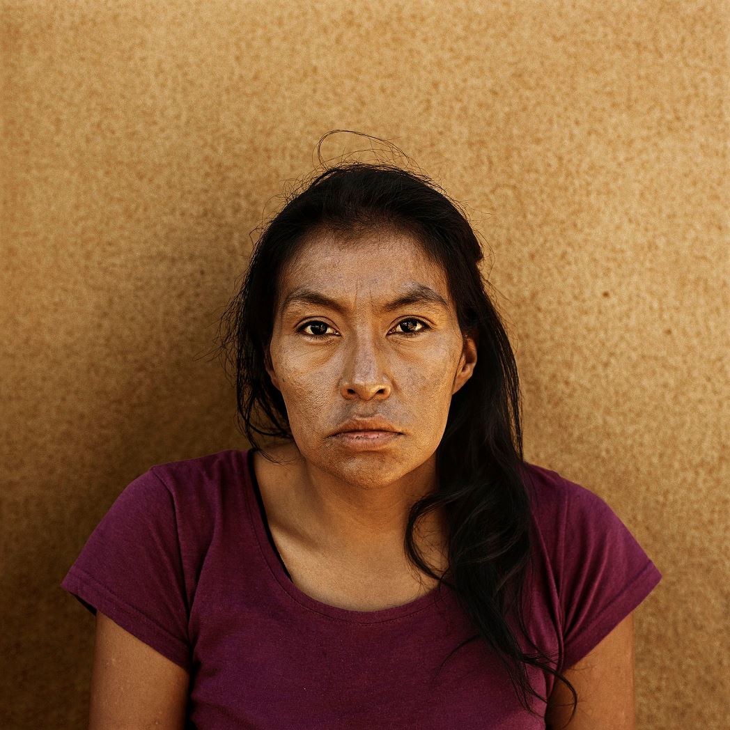 Indian woman with long hair and purple T-shirt.