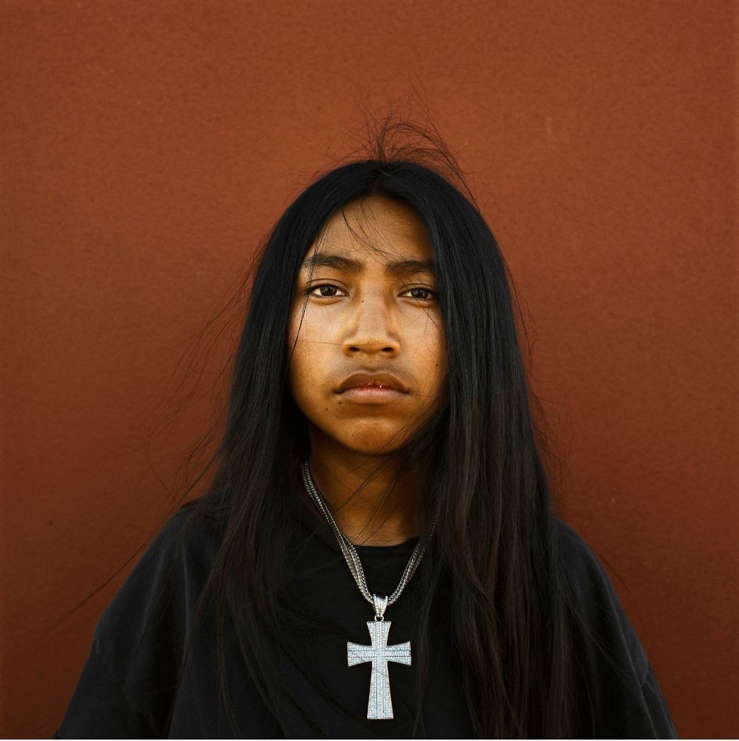 Jeune indien aux cheveux longs portant une croix autour du coup
