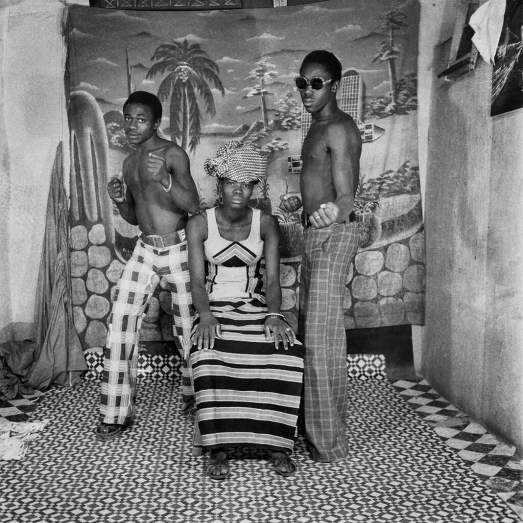 Trois personnes dont deux hommes torse nu  posent dans le studio photo avec toile de fond peinte 