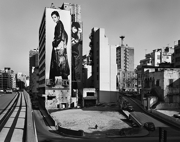 B/W photograph of a street in Beirut showing a fashion advertisement on the full height of the side of two buildings