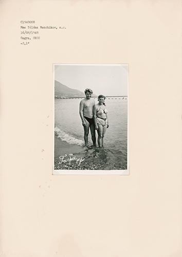 Collée sur une feuille, petite photo N/B montrant un couple qui pose les pieds dans l'eau avec ligne horizon derrière eux.