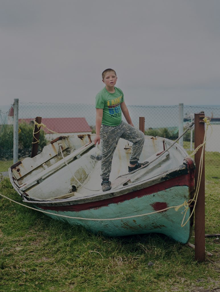 Young boy standing on a boat on land