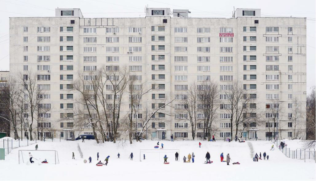 Barre d'immeubles avec personnes qi jouent devant dans la neige